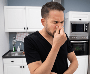 man covering nose in kitchen