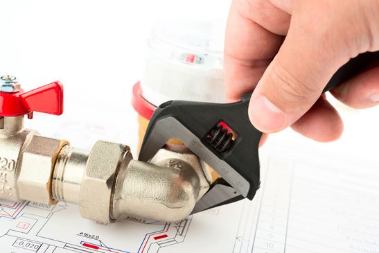 person tightening plumbing fixture with wrench